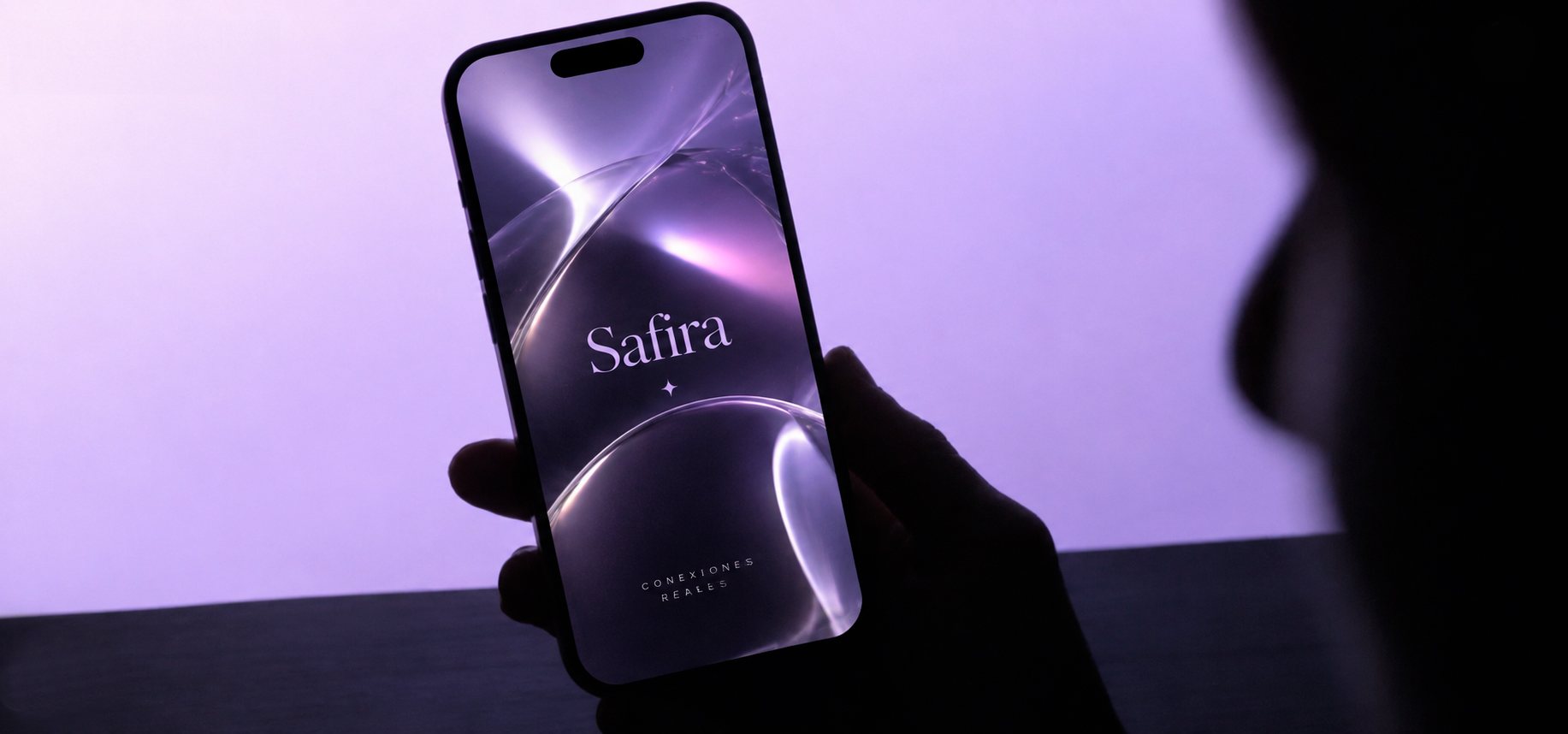 Una persona sostiene su celular con la pantalla de inicio de Safira: Conexiones reales.